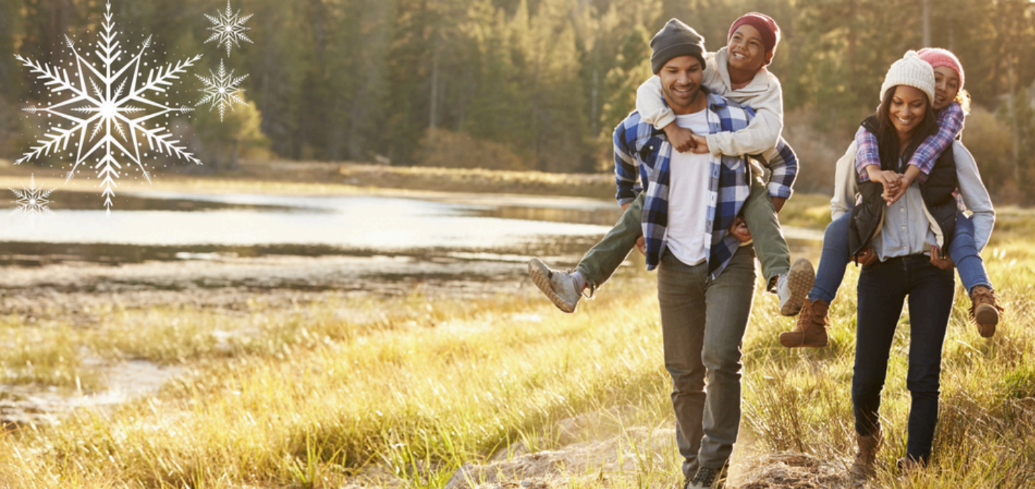 Family walking next to a pond with children riding on their parents' backs